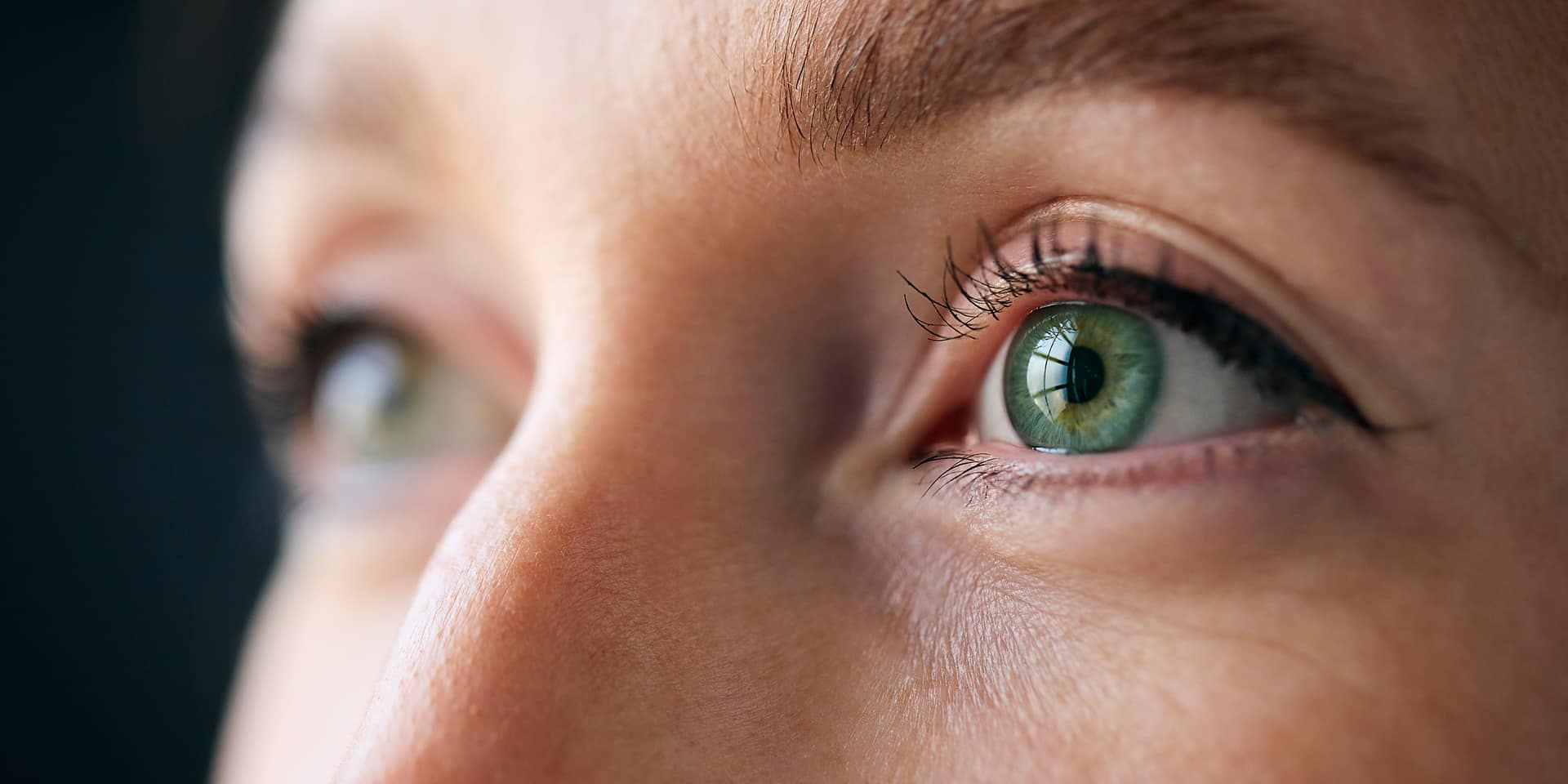 Close-up of a person's face with a striking green eye in sharp focus